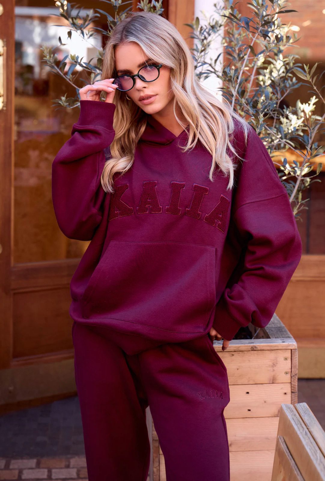 KAIIA The Label model in a burgundy logo hoodie and matching joggers